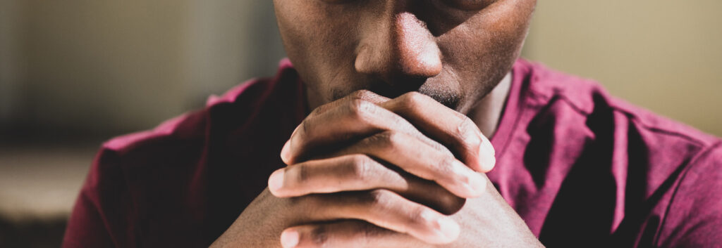Close up of young black man with hands clasped